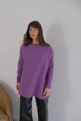 Buzo azul de viscosa con cuello redondo y manga larga. Presenta un aplique con diseño geométrico en el brazo izquierdo.