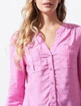 Blusa rosa de lino marca Zac & Rachel, con cuello a la base, escote en V y abertura central con botones. Tiene bolsillos delanteros y mangas largas regulables con presilla y botón.