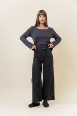 Pantalón de jean negro de pierna ancha y tiro medio-alto, con estampado sutil de leopardo en tono más oscuro y pequeños puntos blancos brillantes.