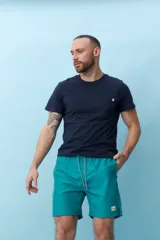 Bermuda de baño color verde agua con cintura elastizada y cordón ajustable. Bolsillos laterales y trasero con etiqueta de marca.