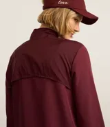 Campera deportiva rompevientos color bordó, con cuello alto, cierre frontal con cremallera, puños elastizados y recortes con hilo reflectante.