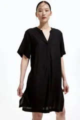 Vestido túnica negro a la rodilla en tejido liviano de viscosa con cuello mao y abertura en V. Modelo de corte holgado con hombros levemente caídos, mangas cortas y bajo recto con tajos laterales.