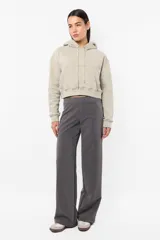 Buzo crop de frisa gamuzada color beige. Diseño con bolsillo canguro delantero, capucha con forrería interna, ojalillos metálicos de marca, cordón ajustable con punteras metálicas, puños y cintura en rib.