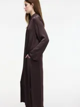 Vestido largo color crema, con cuello mao con lazo ajustable, mangas largas amplias y tajos laterales.
