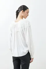 Blusa blanca de estilo boho con escote con volados y lazos, mangas largas abullonadas con puños elásticos.