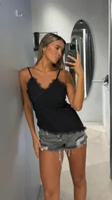 Top negro de tirantes finos con escote en V adornado con encaje negro.