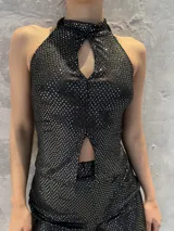 Conjunto de top halter y short de lentejuelas negras. El top tiene un corte en el pecho y un corte en el abdomen.