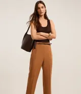 Pantalón de vestir azul marino, de corte zanahoria, con cinturón fino negro con hebilla dorada.