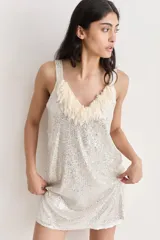 Vestido corto de fiesta, cubierto de lentejuelas plateadas, con escote en V y flecos de tul color crema.