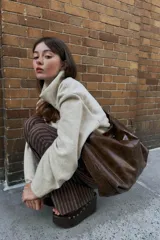 Bolso shopper marrón de efecto acharolado con asa de hombro ajustable, bolsillo interior con cremallera y cierre magnético.