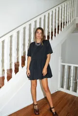 Vestido corto negro con corte en la cintura y falda balloon, de manga corta y cuello redondo.