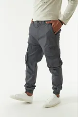 Pantalón cargo gris con puños elásticos, corte regular, bolsillos laterales con solapa y pasacintos.
