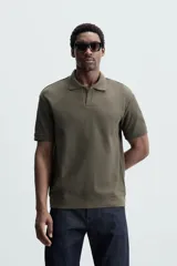 Polo azul marino de punto con textura acanalada vertical, corte regular fit, cuello solapa con abertura frontal y mangas cortas.