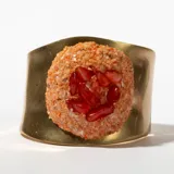 Brazalete rígido dorado con aplique central de piedras rojas y naranjas.