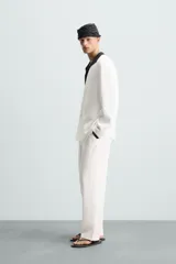 Pantalón blanco de lino con corte relajado (relaxed fit), cintura elástica, bolsillos frontales y un bolsillo trasero de vivo.