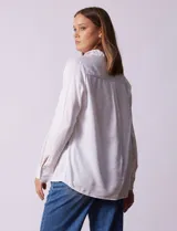 Camisa marrón de lyocell, marca Dash. Cuello con solapa y abertura central con botones. Largo de manga regulable con presilla y botón. Delantera con bolsillos aplicados.