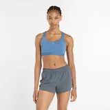 Top deportivo New Balance Essential Train Bra, color celeste, de sujeción media, ideal para entrenamientos dinámicos. Confeccionado en tejido de poliéster elástico con tecnología NB DRY de secado rápido. Cuenta con almohadillas extraíbles y banda elástica inferior.