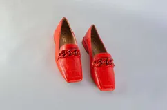 Mocasines fucsia con estampado de piel de serpiente y detalle de cadena plástica en el empeine.