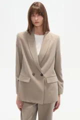 Blazer cruzado de color beige claro, con cuello solapa, dos botones frontales y bolsillos con tapa.
