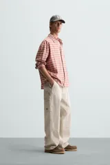 Pantalón gris de corte relaxed fit, con cinco bolsillos, efecto lavado, aplicación de tira y bolsillo multifunción en perneras. Cierre frontal con cremallera y botón.