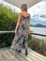 Vestido largo de tirantes con estampado de hojas en tonos marrones y celestes sobre fondo negro.