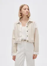 Campera corta de algodón color beige con detalles en blanco, de manga larga y cierre frontal con botones.