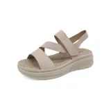 Sandalia de plataforma color beige claro, con tiras anchas cruzadas en el empeine y tira de ajuste con velcro en el talón. La plantilla es acolchada y perforada, y la suela es gruesa y flexible con textura.