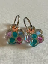 Par de aros colgantes con forma de flor, con pétalos de colores pastel y aro plateado.