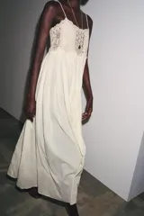 Vestido largo color crudo, de algodón, con tirantes finos y escote recto. Presenta detalle de crochet en la parte superior.