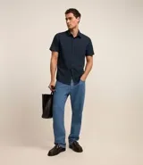 Camisa negra de manga corta, corte slim, con cuello inglés y abotonadura frontal. Confeccionada en viscosa con fibra de bambú.