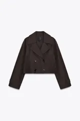 Trench corto color marrón oscuro con cuello solapa, doble botonadura y mangas largas con trabillas. Presenta bolsillos delanteros de vivo y corte holgado.