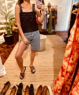 Musculosa de lentejuelas negra con breteles de cuero bordados, de corte ajustado.