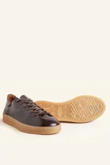 Zapatilla de cuero vacuno color azul marino, con cordones azules y suela de caucho color caramelo.