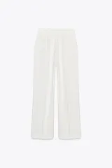 Pantalón de tiro alto color blanco, de corte recto y pierna ancha, con bolsillos laterales y pinzas frontales.