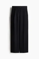 Pantalón sastrero negro de sarga con pinzas, corte holgado, tiro alto, pretina prolongada con botón, bolsillos al bies y bolsillos insertados atrás. Piernas anchas con pliegues adelante y atrás.
