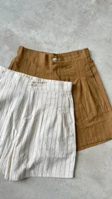 Short color ocre con finas rayas verticales blancas, tiro alto, bolsillos laterales y botón de madera.