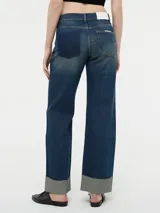 Pantalón de jean azul oscuro, de corte ancho y tiro alto, con bolsillos delanteros y traseros, y dobladillo en el ruedo.