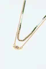 Set de dos collares dorados. Uno es una cadena con cuentas verdes y blancas. El otro es una cadena con un dije de ojo turco con incrustaciones de strass azul.