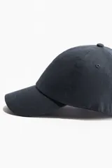 Gorra azul de lino y algodón con ojales bordados en la parte superior y trabilla ajustable con hebilla de metal atrás.