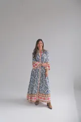 Vestido largo celeste con estampado abstracto en tonos azules, marrones y rosados. Tiene cuello mao, mangas 3/4 acampanadas y cierre frontal con botones.