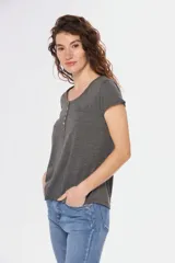 Remera color beige con escote redondo, manga corta, bolsillo en el pecho y cierre parcial con botones.