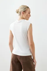 Remera blanca de corte ajustado, con cuello alto y sin mangas.