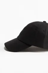 Gorra negra de lino y algodón con ojales bordados en la parte superior y trabilla ajustable con hebilla de metal atrás. Cinta antitranspirante de algodón.