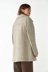 Abrigo de lana color beige con cuello solapa y manga larga. Cierre frontal cruzado doble con botones dorados. Bolsillos delanteros plaqué y forro al tono. Tela 100% lana fina sin teñir, diseñada exclusivamente por Don Baez. Hecho 100% en Uruguay.