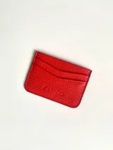 Tarjetero rojo de cuero vacuno con cuatro divisiones para tarjetas y un bolsillo central.