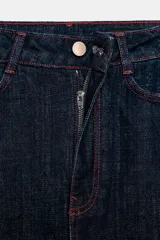 Falda midi de tiro alto confeccionada en denim oscuro, con cinco bolsillos estilo jean, cierre frontal con cremallera y botón, y abertura en la espalda. Presenta pespuntes en color rojo contrastante.