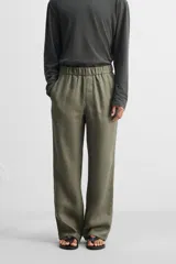 Pantalón negro regular fit confeccionado en tejido de lino. Cintura ajustable con cordón interior, bolsillos frontales y detalle de bolsillos traseros de vivo.