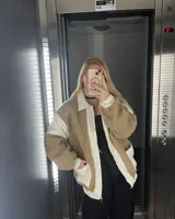 Campera con cuerpo de corderito color beige y mangas de tela lisa color blanco.