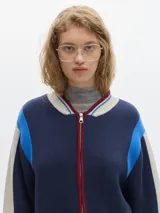 Campera tejida con cierre delantero, bordado en la espalda, de color rojo con detalles marrones y grises.