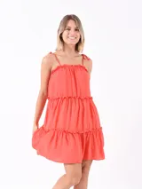 Vestido corto color naranja oscuro, con breteles finos, escote recto con volados y falda escalonada con volados.